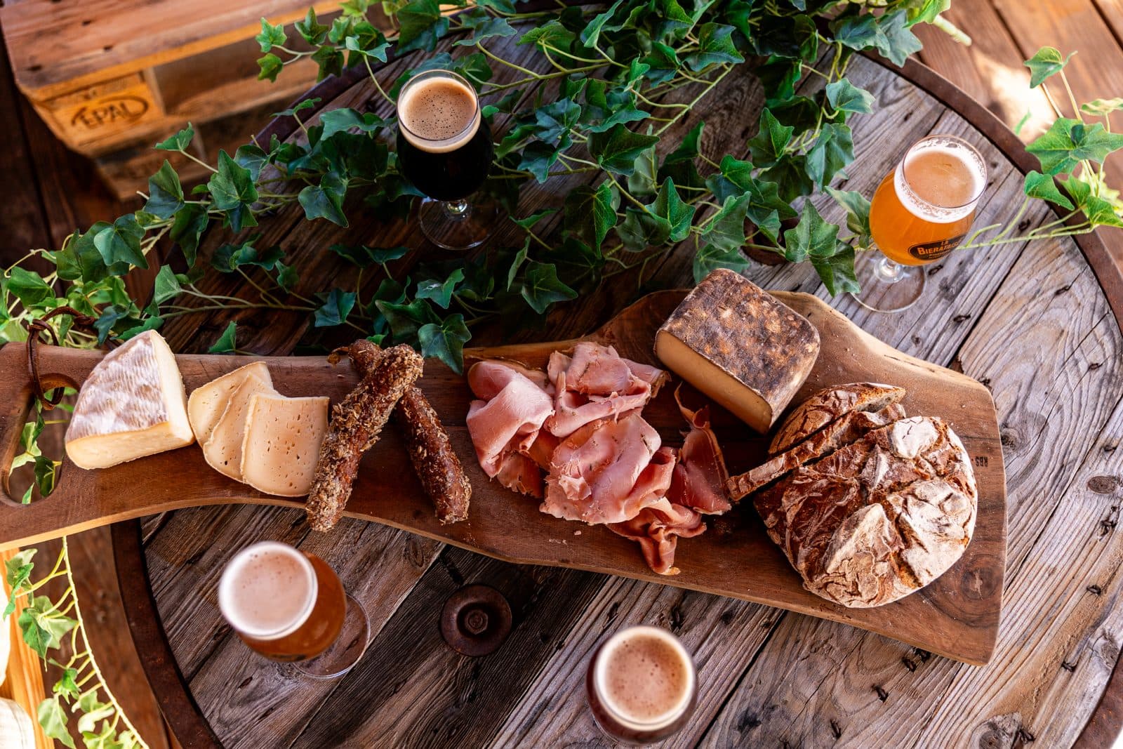 Planche de charcuterie, fromages et pain de campagne servie avec des bières à la brasserie